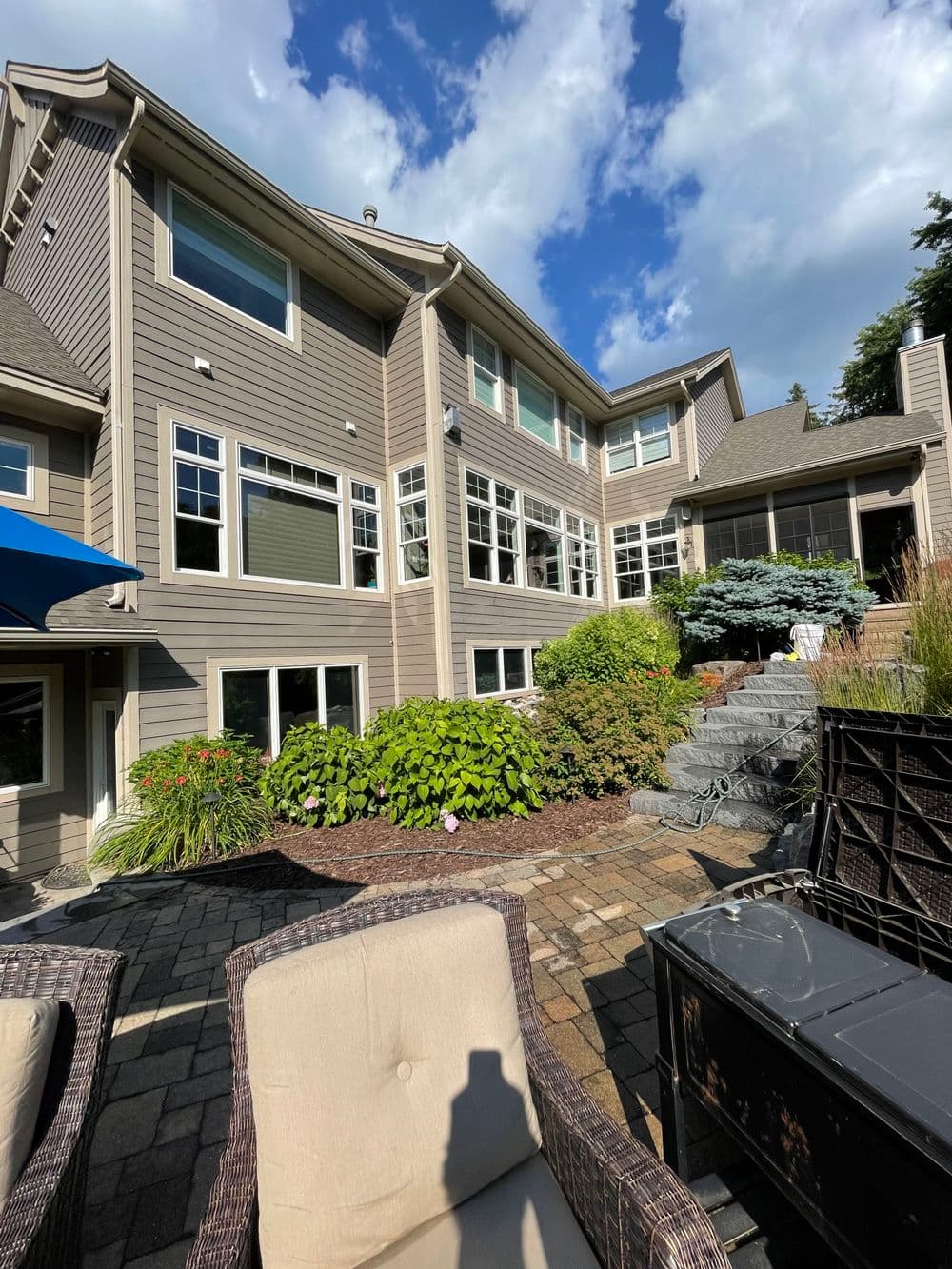 Modern home exterior with large windows, stone pathway, and landscaped garden.