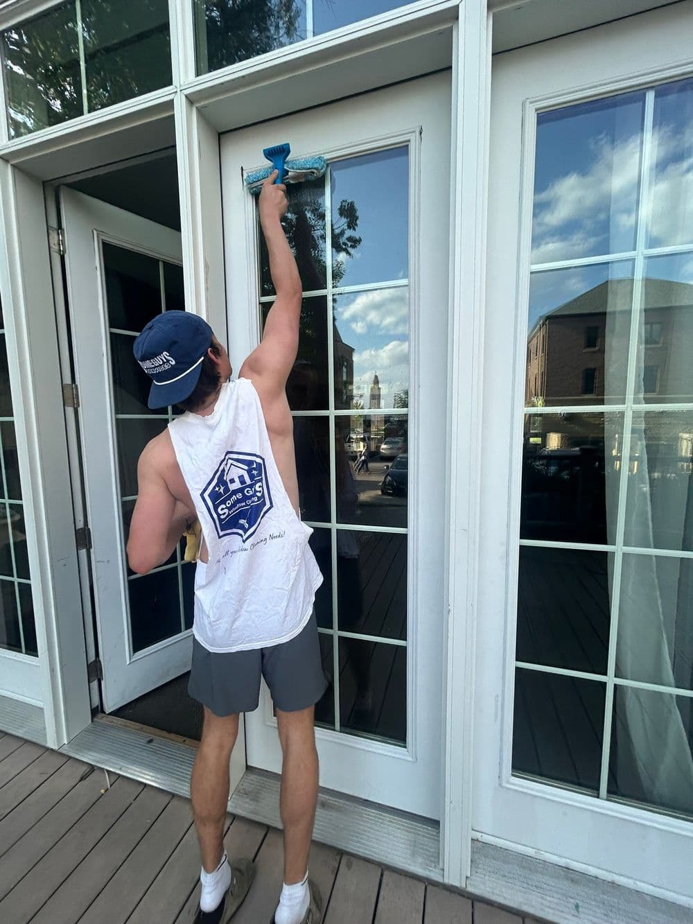 Person cleaning large glass door with a squeegee on a sunny day.
